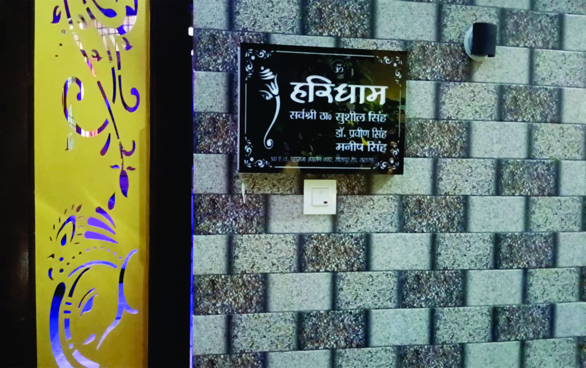 A beautiful black color name plate in Lucknow with the name Haridham is hanging on a black and white wall.