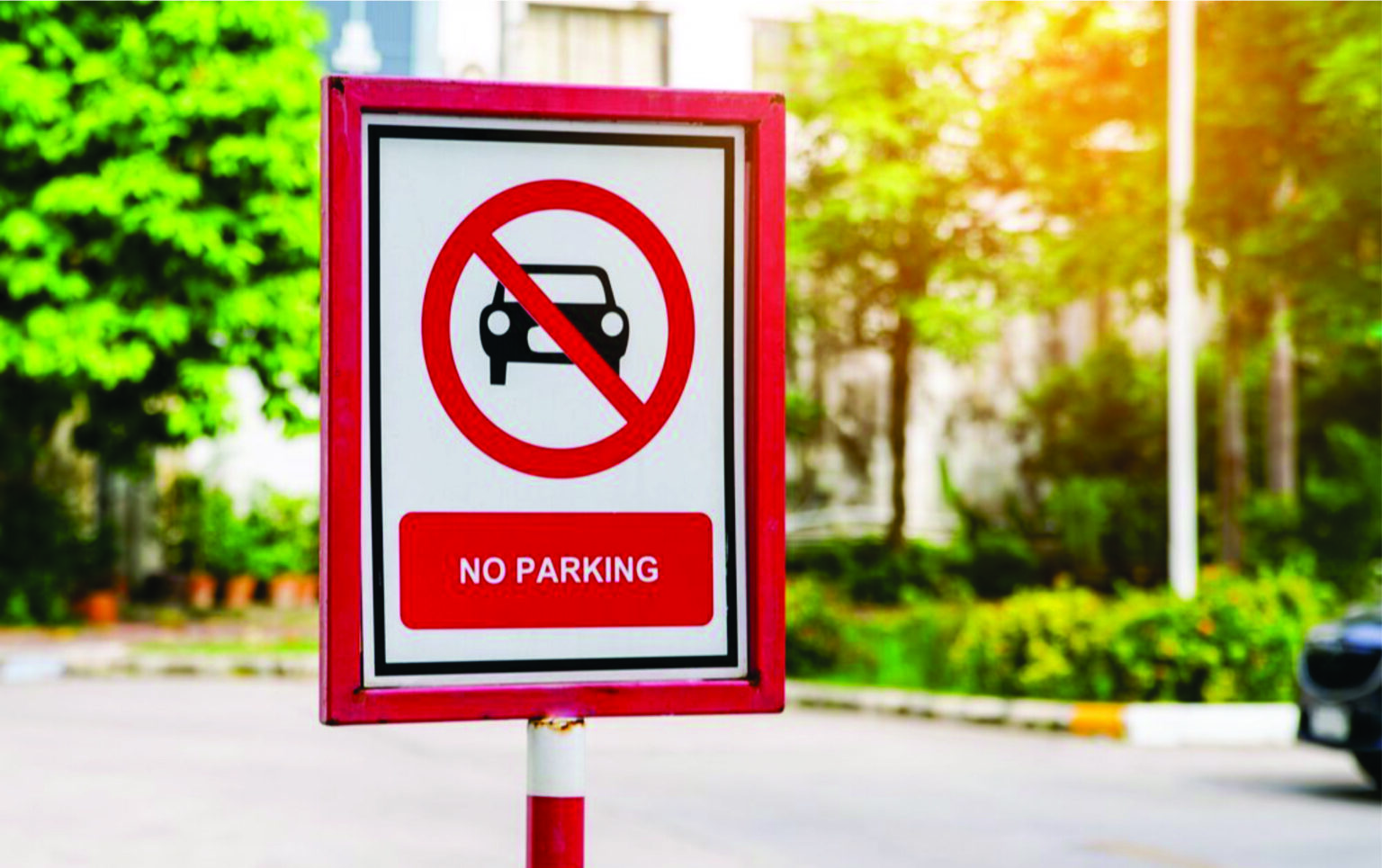 A signage board of no parking stand on campus with garden and road background area in Lucknow